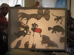 This may contain: people standing around looking at an art work with shadow cast on the back of it